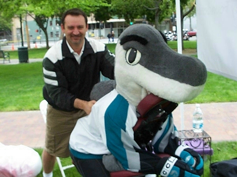 Edward Cefalu provides a chair massage to the NHL's San Jose Sharks mascot, Sharky.